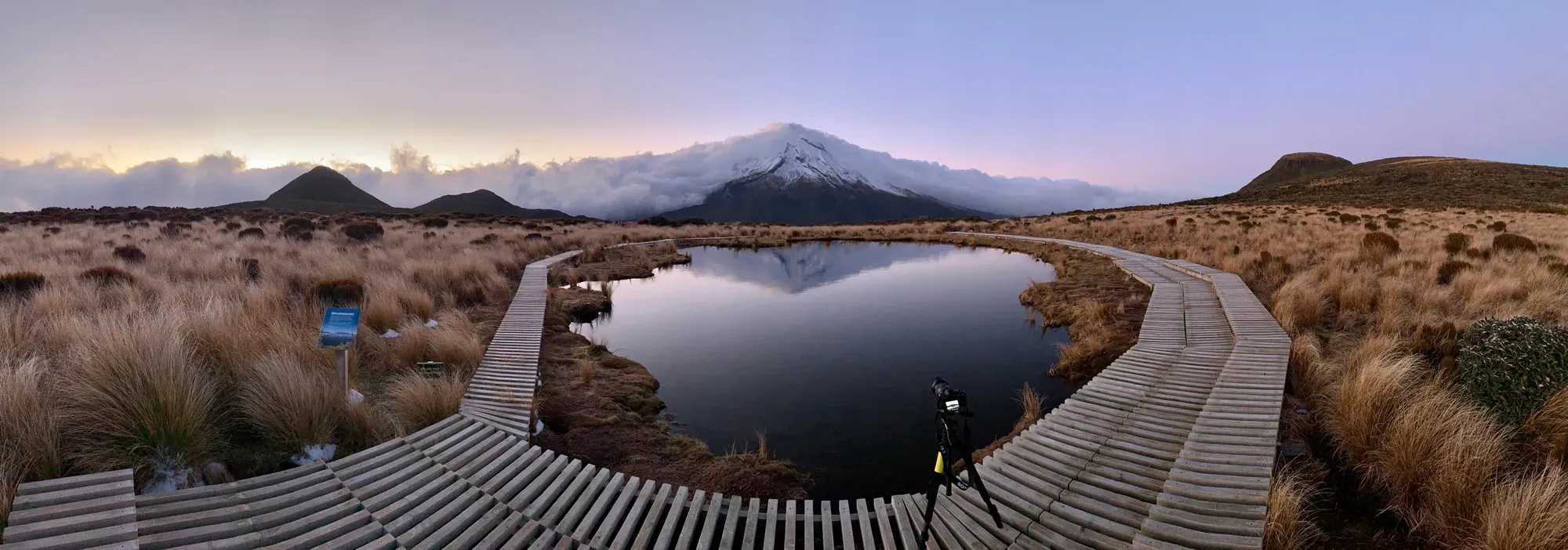 Panorama of the reflective tarn and boardwalk with Mount Taranaki behind