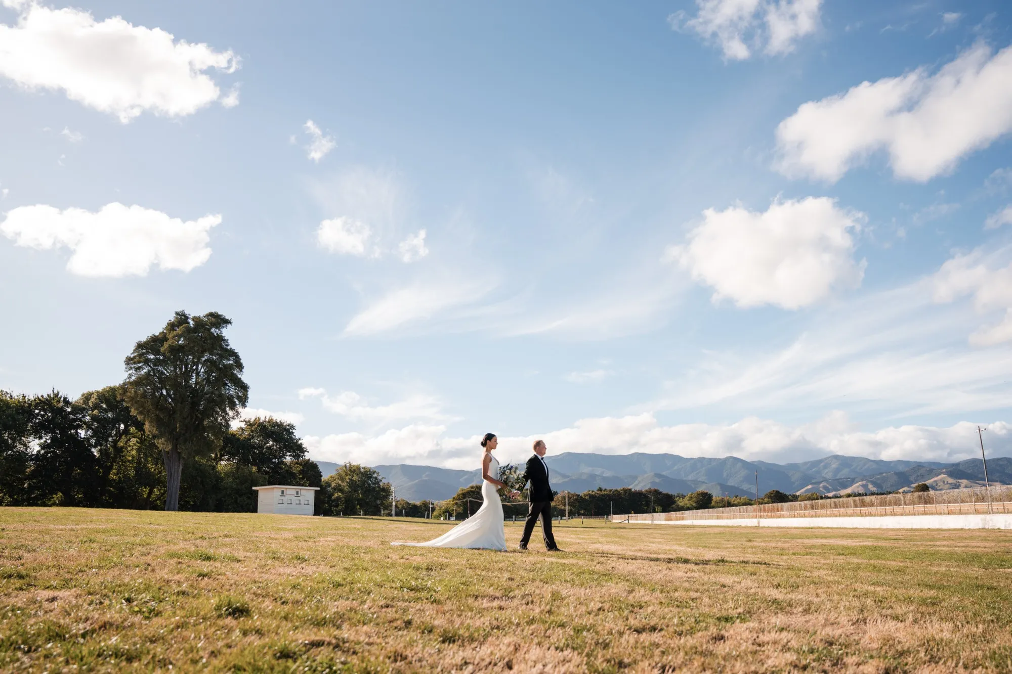 Bride and groom standing in an open field under a big sky